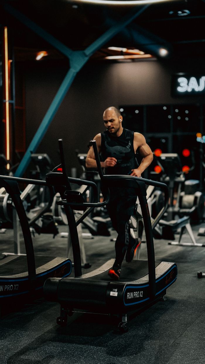 A determined man running on a treadmill in a modern gym setting, emphasizing fitness and energy.